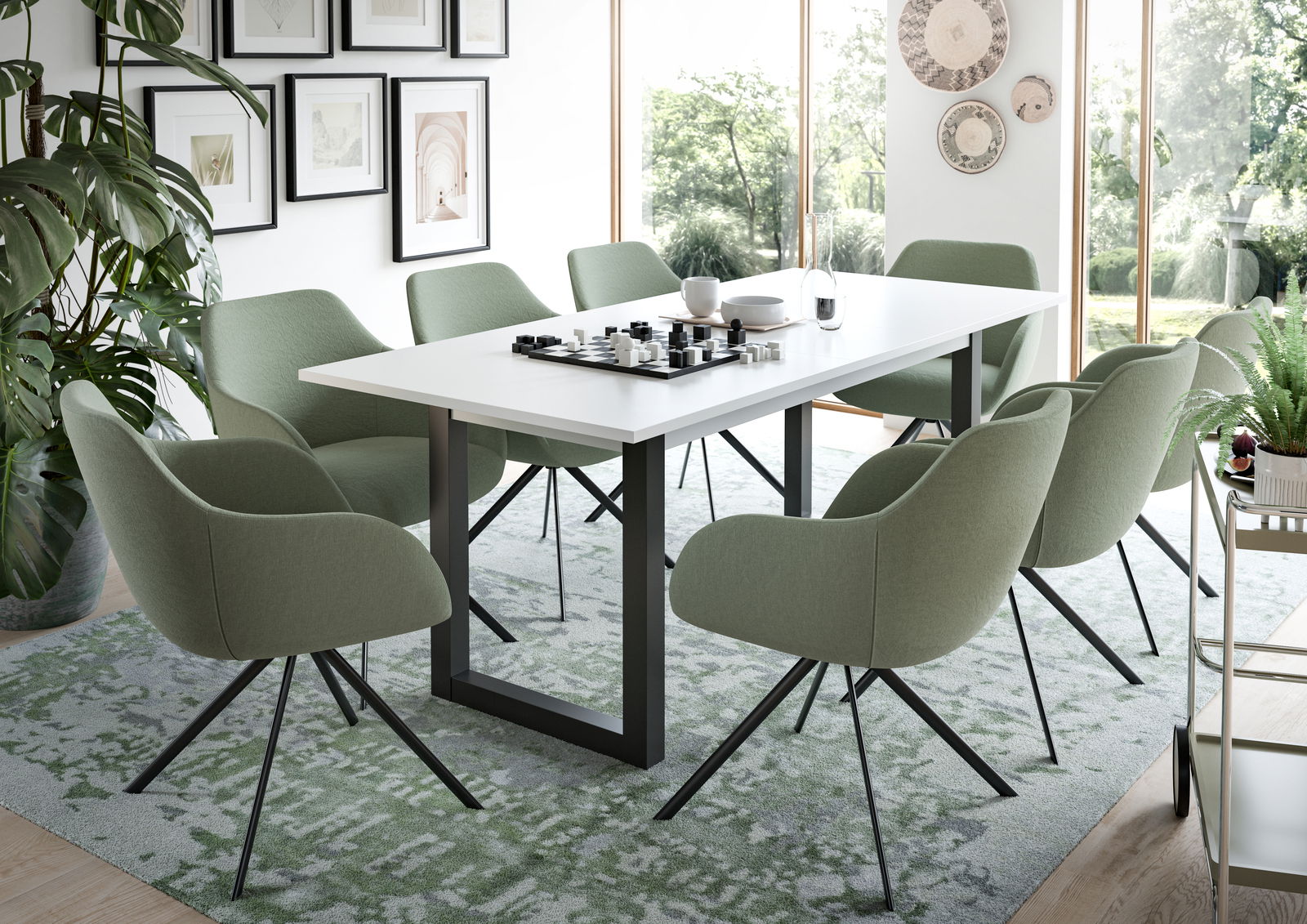 Moderner Esstisch mit weißer Tischplatte und schwarzen Metallbeinen, umgeben von grünen Stühlen in einem hellen Raum mit großen Fenstern, seitliche Perspektive.