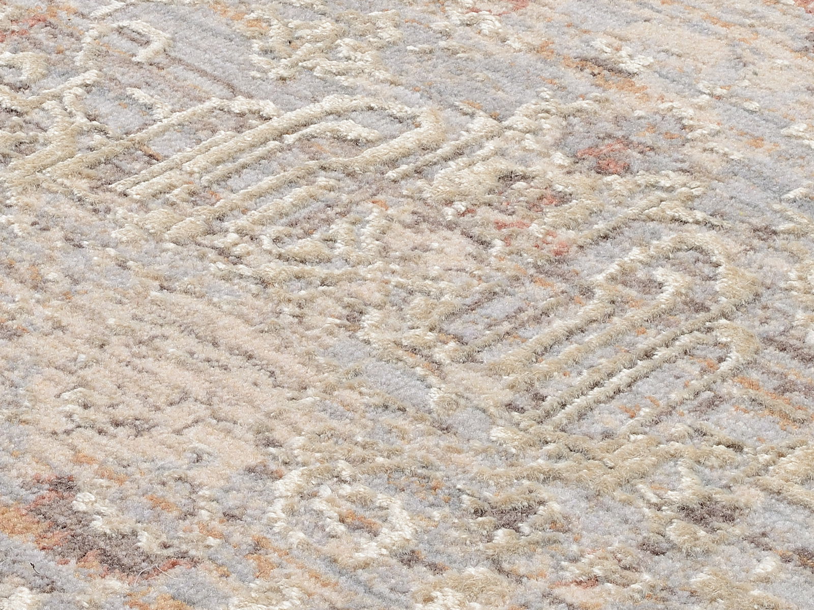 Nahaufnahme eines Designer-Teppichs mit abstraktem Muster in Beige- und Grautönen, seitliche Perspektive