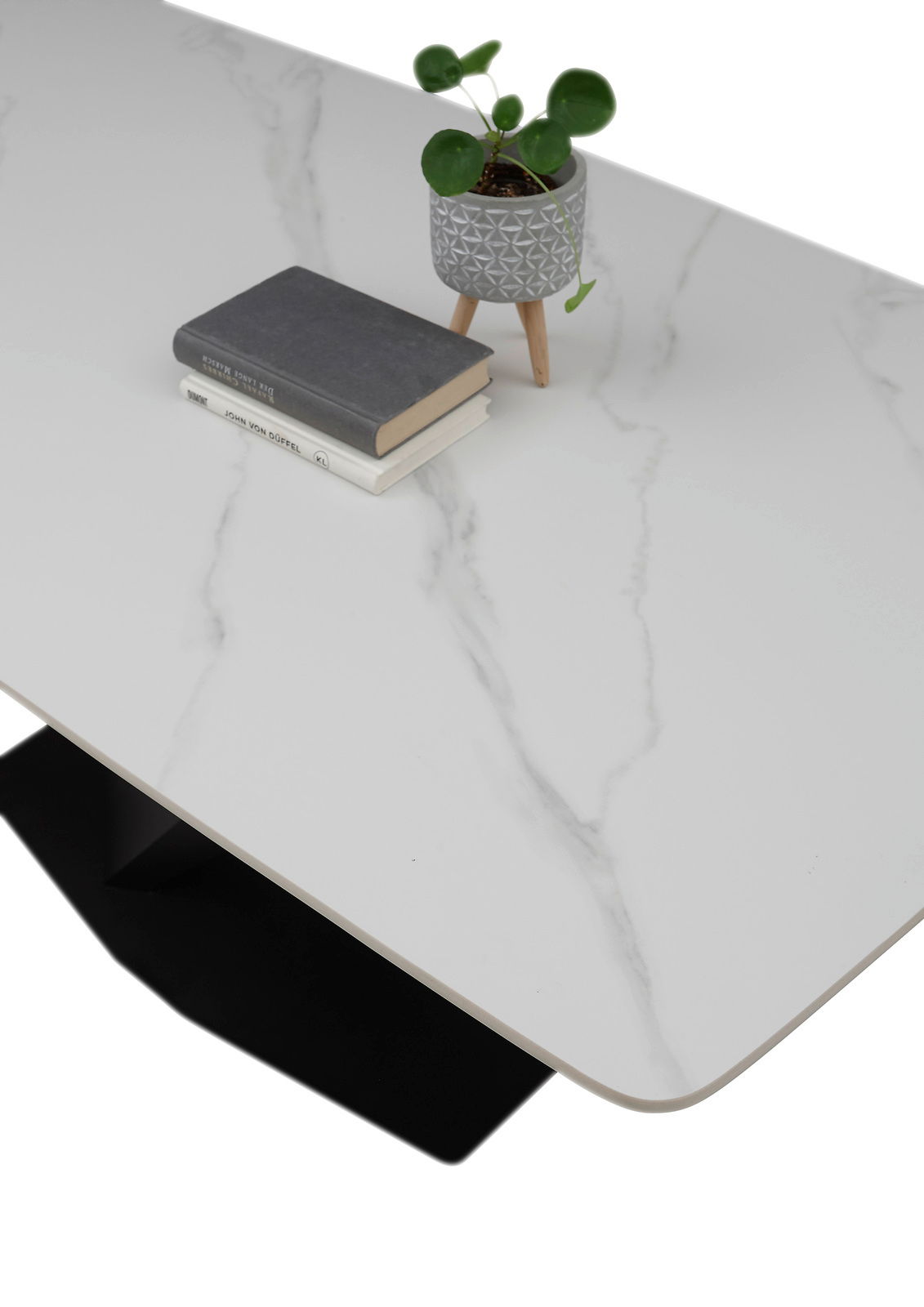Moderner Esstisch mit weißer Marmoroptik-Oberfläche, dekoriert mit einem kleinen Pflanzentopf und Büchern, aus der Vogelperspektive.