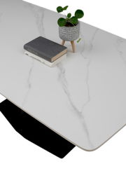 Moderner Esstisch mit weißer Marmoroptik-Oberfläche, dekoriert mit einem kleinen Pflanzentopf und Büchern, aus der Vogelperspektive.