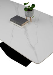 Moderner Esstisch mit weißer Marmoroptik-Oberfläche, dekoriert mit einem kleinen Pflanzentopf und Büchern, aus der Vogelperspektive.