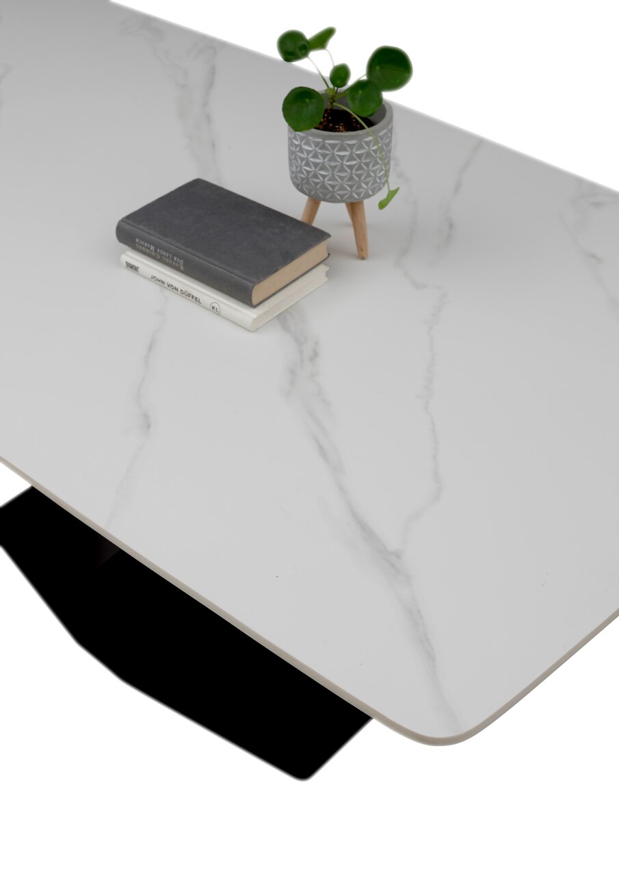 Moderne eettafel met een blad in witte marmerlook, versierd met een kleine plantenpot en boeken, gezien vanuit vogelperspectief.