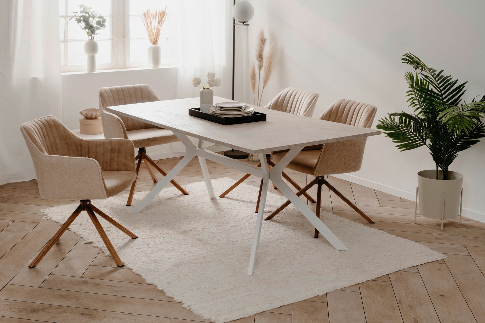 Z2 Esstisch ONEX Moderner Esstisch mit heller Tischplatte und weißen Metallbeinen, umgeben von vier beigen Stühlen auf einem hellen Teppich in einem hellen Raum mit Pflanzen und Dekorationen. Perspektive von schräg oben.