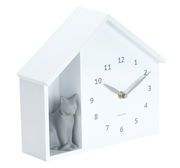 Weiße Wanduhr in Form eines Hauses mit einer grauen Katzenfigur auf der linken Seite, seitliche Perspektive.