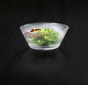 Glasierte Schale mit geriffeltem Design, gefüllt mit frischem Salat, aus seitlicher Perspektive fotografiert.