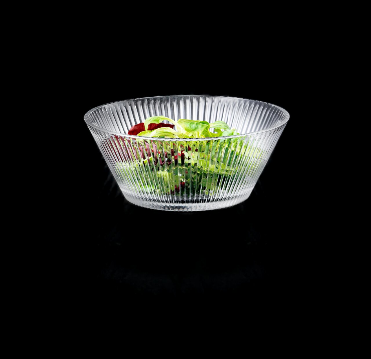 Glasierte Schale mit geriffeltem Design, gefüllt mit frischem Salat, aus seitlicher Perspektive fotografiert.