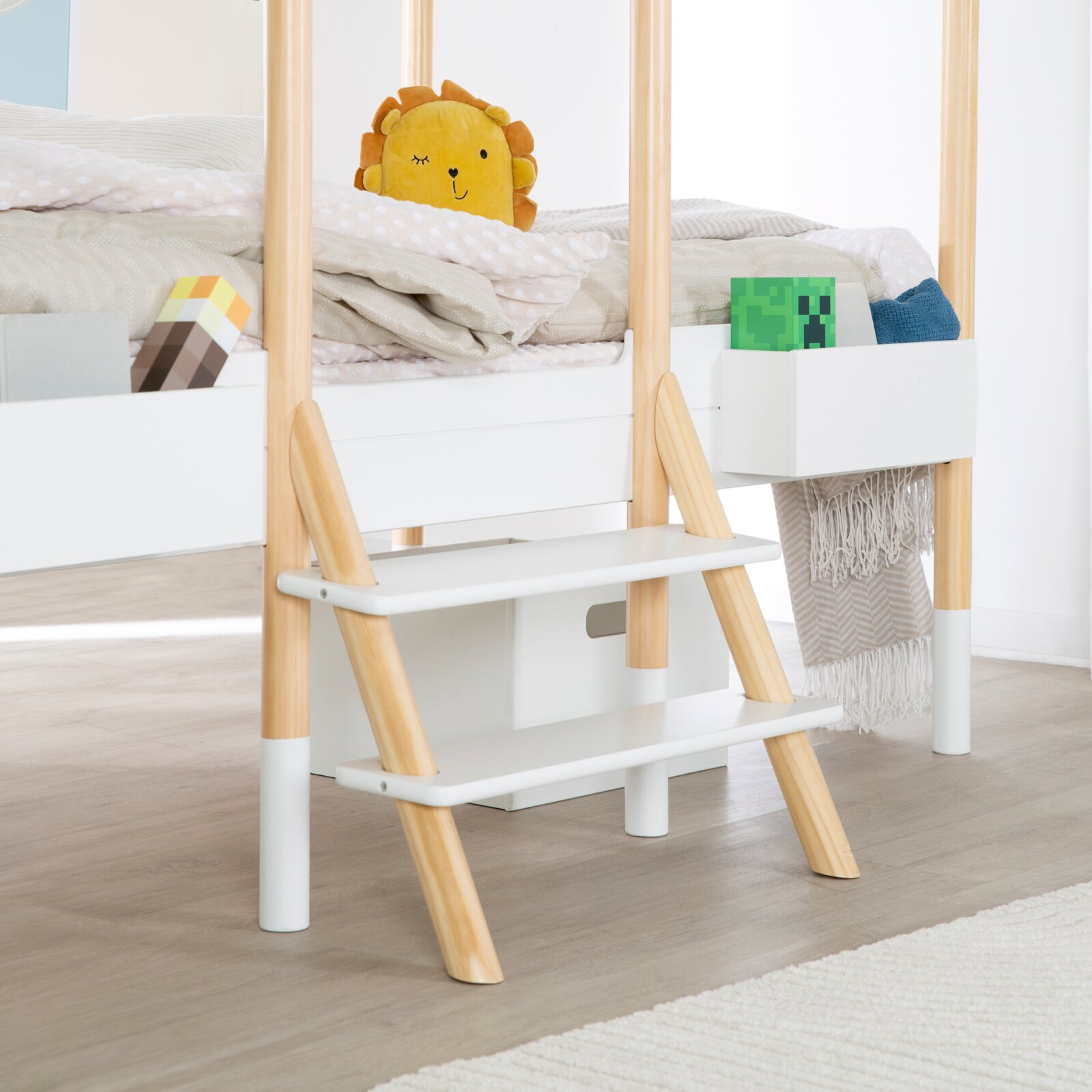 Kinder-Hochbett in Weiß und Naturholz mit schräger Leiter, zwei breiten Stufen und seitlicher Aufbewahrungsbox, aus frontaler Perspektive leicht von rechts dargestellt