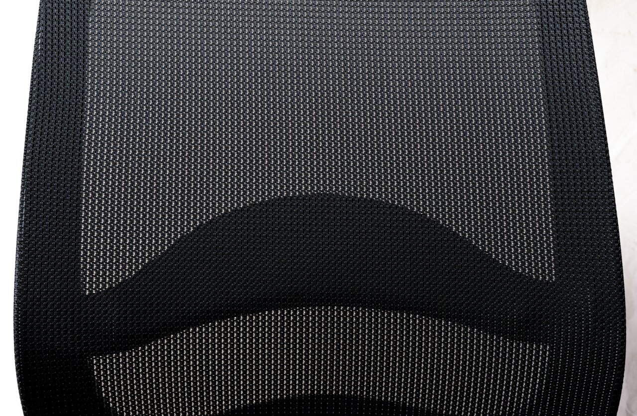 Nahaufnahme der Rückenlehne eines Drehstuhls aus schwarzem Netzgewebe, von oben betrachtet.