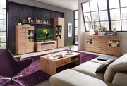 Moderne Wohnwand mit Sideboard und Couchtisch aus Holz in einem hellen Wohnzimmer mit großen Fenstern, seitliche Perspektive.