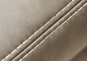 Nahaufnahme einer Polsterrundecke mit feiner Naht und glatter, beiger Lederoberfläche, seitliche Perspektive.