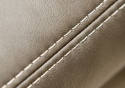 Nahaufnahme einer Polsterrundecke mit feiner Naht und glatter, beiger Lederoberfläche, seitliche Perspektive.