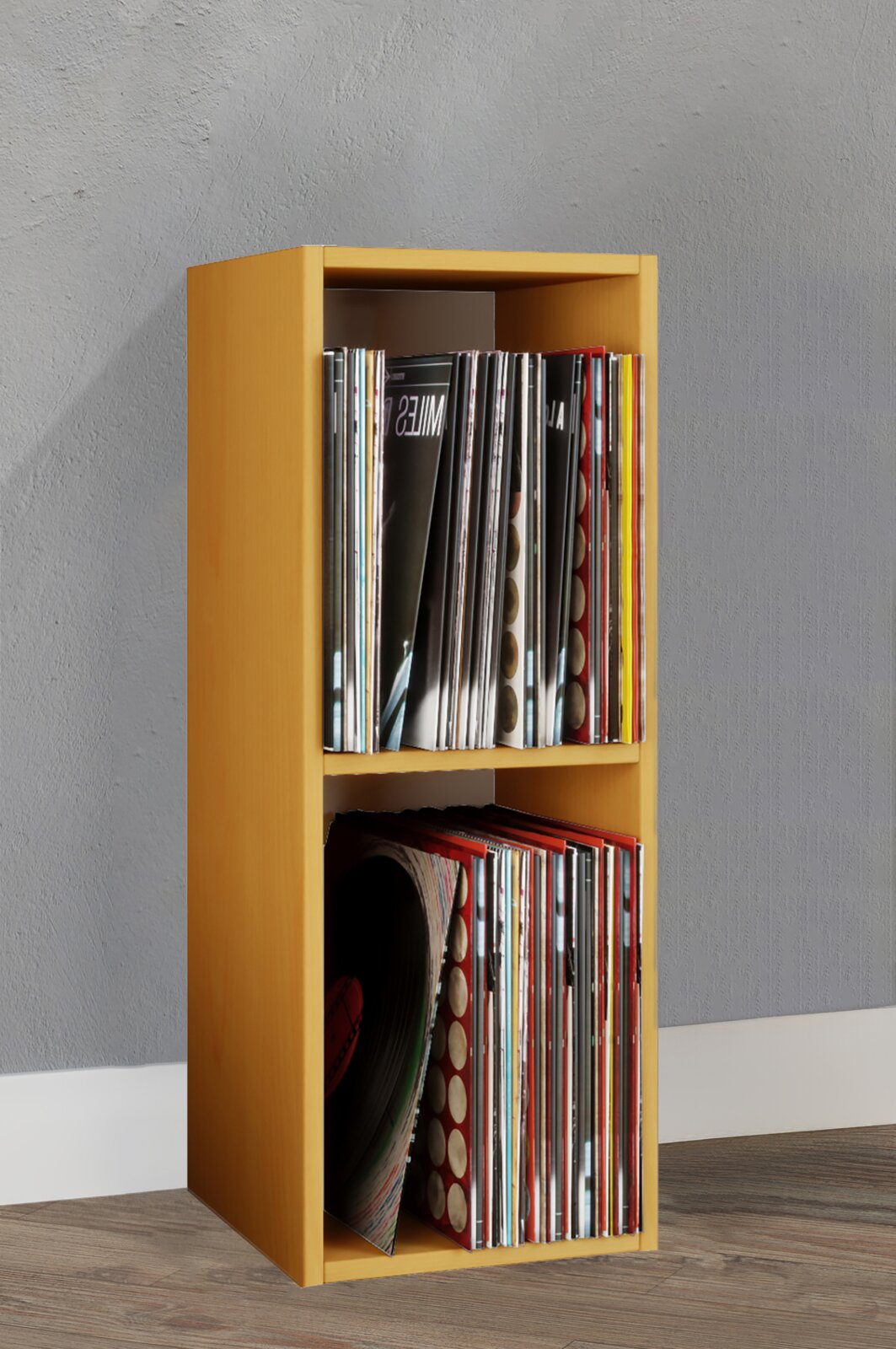 Gelbes, schmales Holz-Regal für Schallplatten mit zwei Fächern, gefüllt mit Vinyl-Covern, freistehend vor grauer Wand; Perspektive: frontale Ansicht mit leichtem Blick von links oben.
