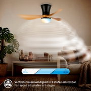 Onderaanzicht van een draaiende plafondventilator met drie houtkleurige bladen, zwarte behuizing, geïntegreerde verlichting en drie instelbare snelheden in een sfeervolle woonkamer.
