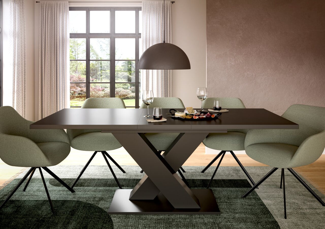 MID.YOU Esstisch MOTION Moderner Esstisch mit X-förmigem Gestell, umgeben von grünen Stühlen, in einem hellen Raum mit großem Fenster, aus der Frontalperspektive.