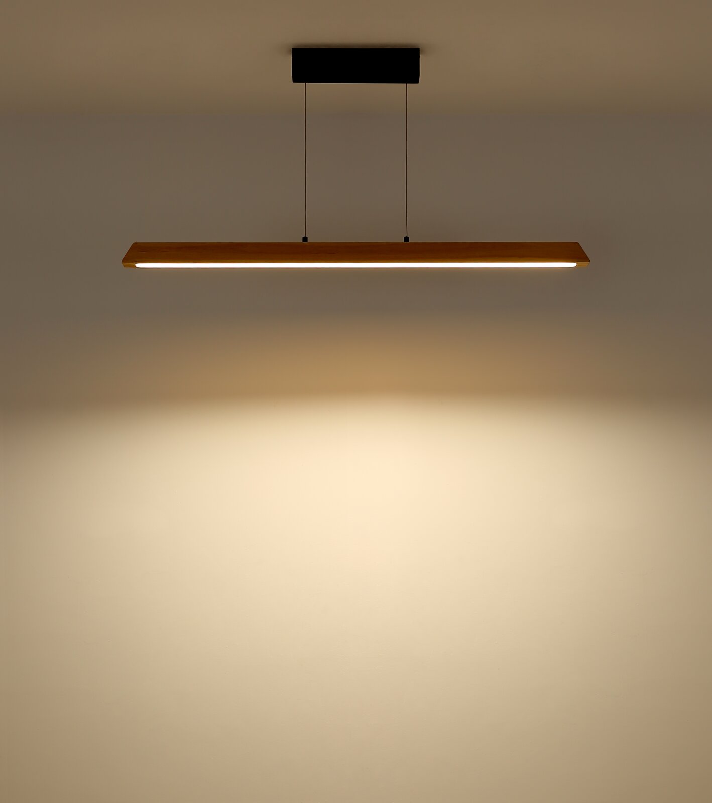 Moderne LED-Pendelleuchte mit langem Holz-Balken und warmweißem Licht, an zwei schwarzen Kabeln von einer schwarzen Deckenhalterung abgehängt, Frontalansicht leicht von unten.