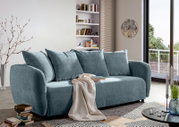 Modernes Funktionssofa in hellblauem Stoff, seitliche Perspektive, dekoriert mit Kissen und Decke, in einem stilvollen Wohnzimmer mit Bücherregal und großem Fenster.