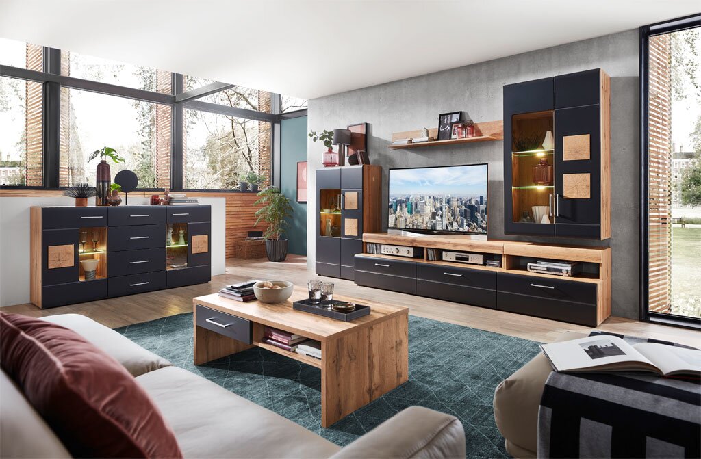 Moderne Wohnzimmermöbel in einem hellen Raum mit großen Fenstern, bestehend aus einem Sideboard, einem Couchtisch und einer Wohnwand in Holzoptik und dunklen Fronten. Perspektive: Frontalansicht.
