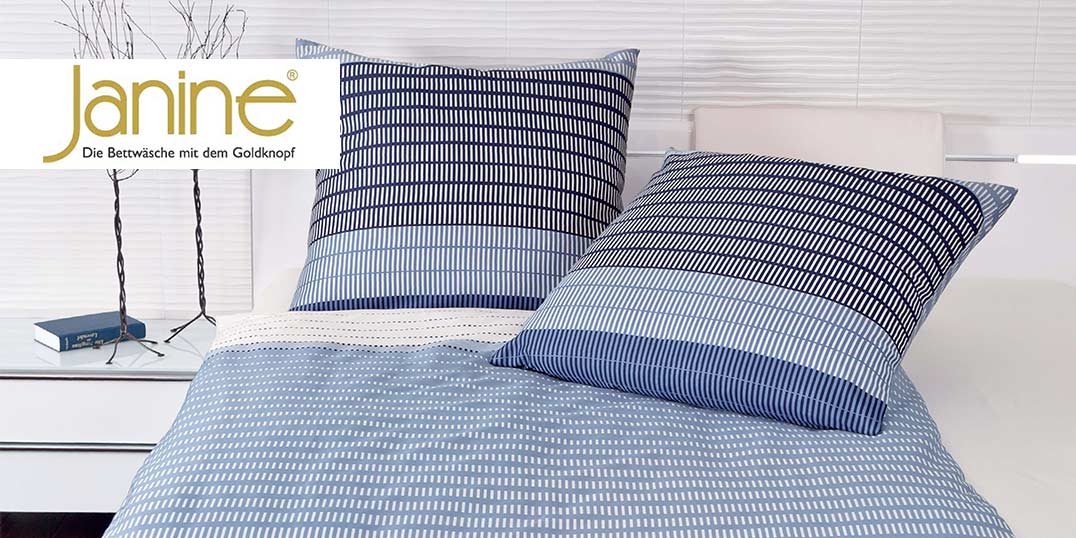 Blau-weiß gestreiftes Bettwäscheset mit zwei passenden Kissen auf einem weißen Bett.