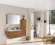 Moderne badkamerkast in houtlook, rechts aan de muur bevestigd, gezien vanaf de zijkant.