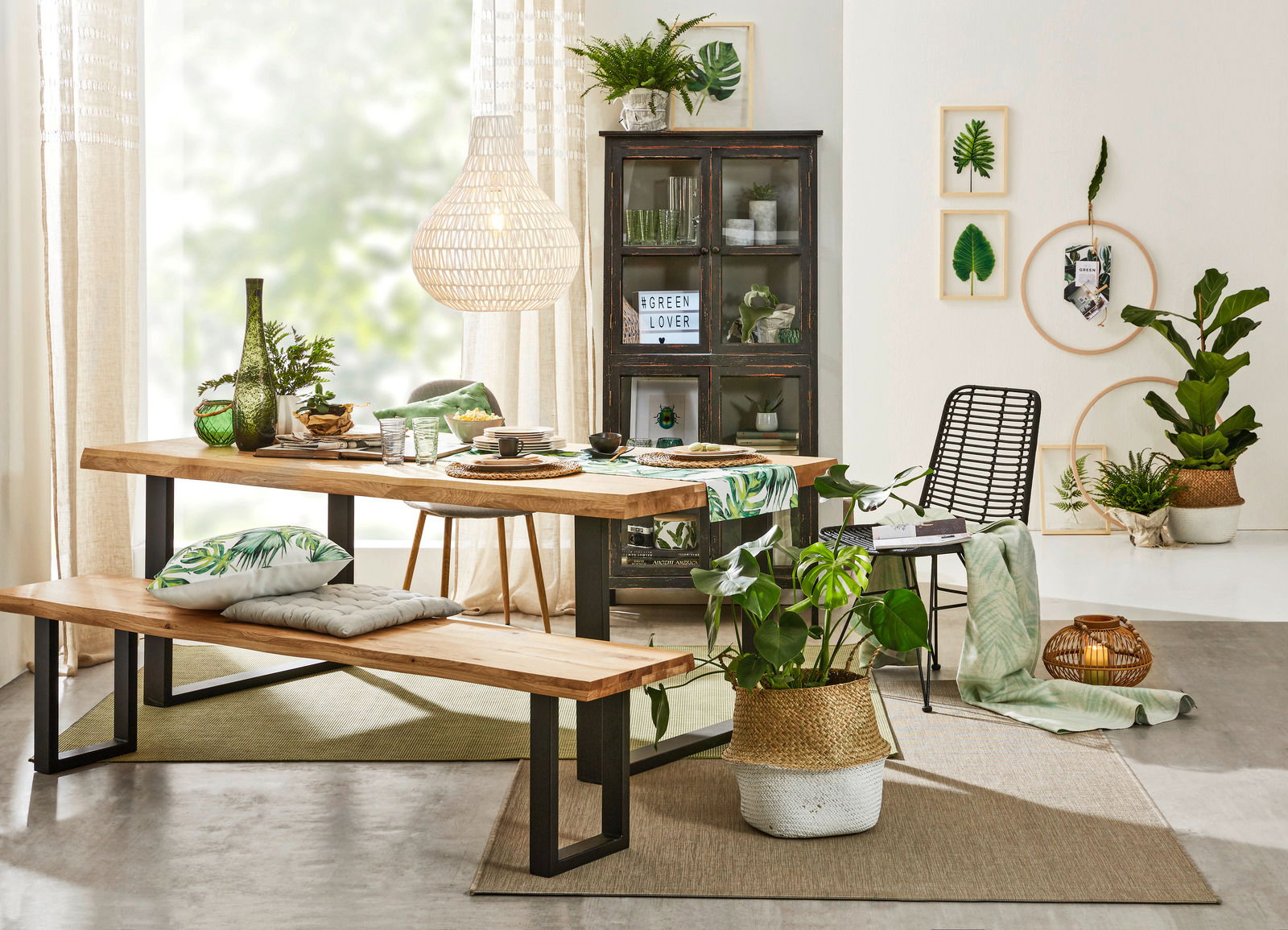 Moderner Esstisch aus Holz mit schwarzem Metallgestell, dekoriert mit grünen Pflanzen und Geschirr, seitliche Perspektive.