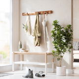 Wandgarderobe mit Haken, an der ein Mantel, eine Tasche und ein Regenschirm hängen, daneben eine Bank und eine Pflanze, seitliche Perspektive