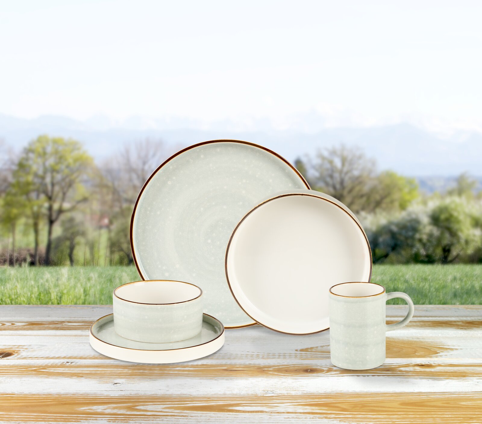10-delige servieset in een natuurlijke omgeving, bestaande uit borden, kopjes en schalen, gepresenteerd op een houten tafel.