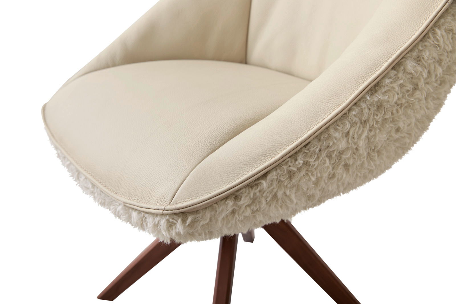 Nahaufnahme eines Armlehnstuhls mit cremefarbenem Lederbezug und flauschiger Außenseite, seitliche Perspektive