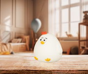 Niedliches Akku-Nachtlicht in Form eines Huhns, auf einem Tisch in einem gemütlichen Kinderzimmer platziert, seitliche Perspektive.