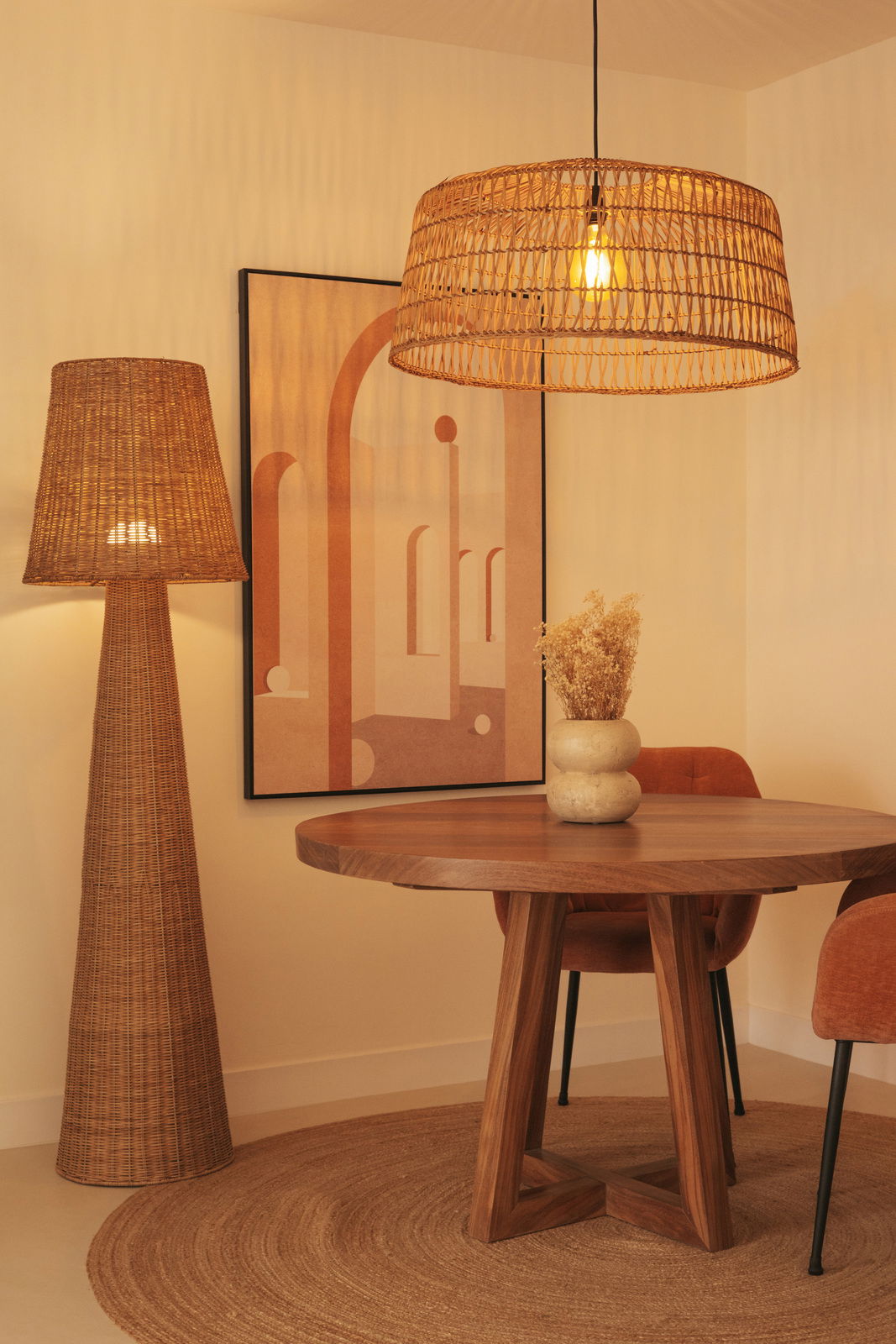 Rattan Outdoor-Stehleuchte in einem stilvoll eingerichteten Raum mit Holztisch und Kunstwerk an der Wand, seitliche Perspektive.