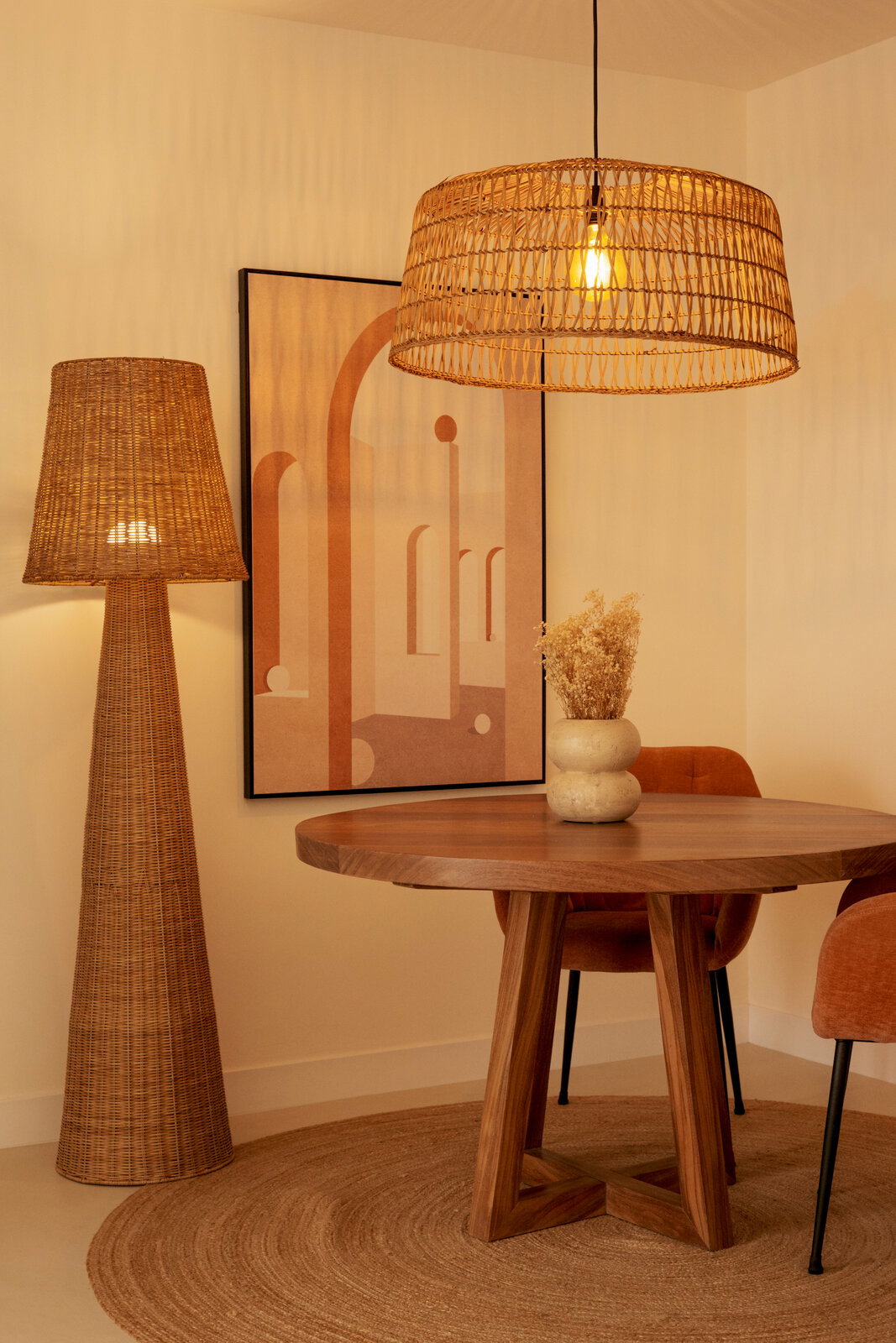 Rattan Outdoor-Stehleuchte in einem stilvoll eingerichteten Raum mit Holztisch und Kunstwerk an der Wand, seitliche Perspektive.