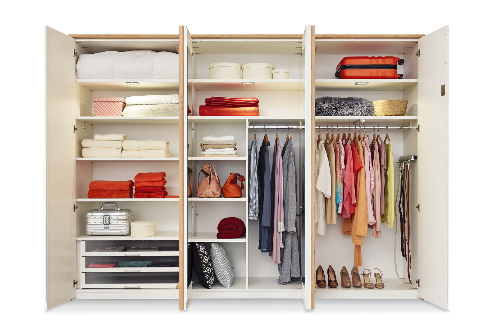 Offener 6-türiger Drehtürenschrank mit verschiedenen Fächern, Kleiderstangen und Regalen, gefüllt mit Kleidung, Handtüchern und Accessoires, aus frontaler Perspektive.