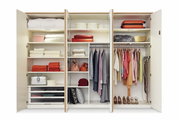 Offener 6-türiger Drehtürenschrank mit verschiedenen Fächern, Kleiderstangen und Regalen, gefüllt mit Kleidung, Handtüchern und Accessoires, aus frontaler Perspektive.