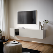 Modernes TV-Hängelowboard in Weiß, seitliche Perspektive, mit dekorativen Vasen und Pflanzen, unter einem an der Wand montierten Fernseher.