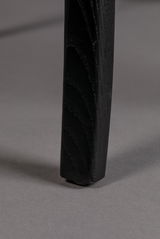 Nahaufnahme eines schwarzen Stuhlbeins auf grauem Hintergrund, von der Seite betrachtet.