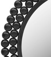 Nahaufnahme eines runden Spiegels mit dekorativem schwarzen Kugelrahmen, perspektivisch von der Seite aufgenommen.