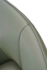 Nahaufnahme eines grünen Armlehnstuhls aus Leder, Fokus auf die Naht und Textur der Rückenlehne.