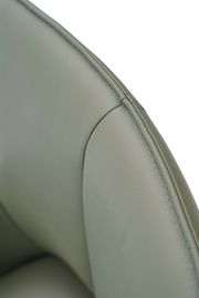 Nahaufnahme eines grünen Armlehnstuhls aus Leder, Fokus auf die Naht und Textur der Rückenlehne.