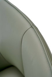 Nahaufnahme eines grünen Armlehnstuhls aus Leder, Fokus auf die Naht und Textur der Rückenlehne.