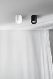 Zwei zylindrische Aufbauspots in Schwarz und Weiß an der Decke, seitliche Perspektive