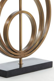 Nahaufnahme eines dekorativen Lampenfußes aus Metall mit kreisförmigem Design auf einem rechteckigen Sockel, seitliche Perspektive.