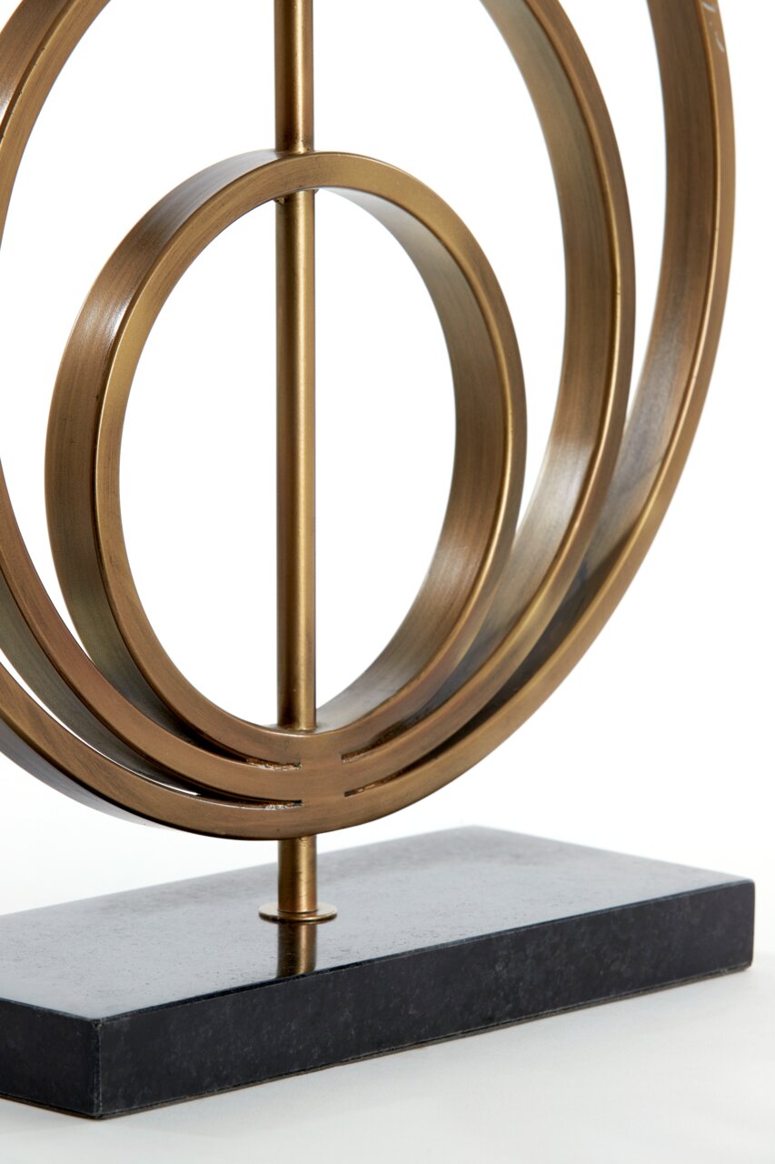 Nahaufnahme eines dekorativen Lampenfußes aus Metall mit kreisförmigem Design auf einem rechteckigen Sockel, seitliche Perspektive.