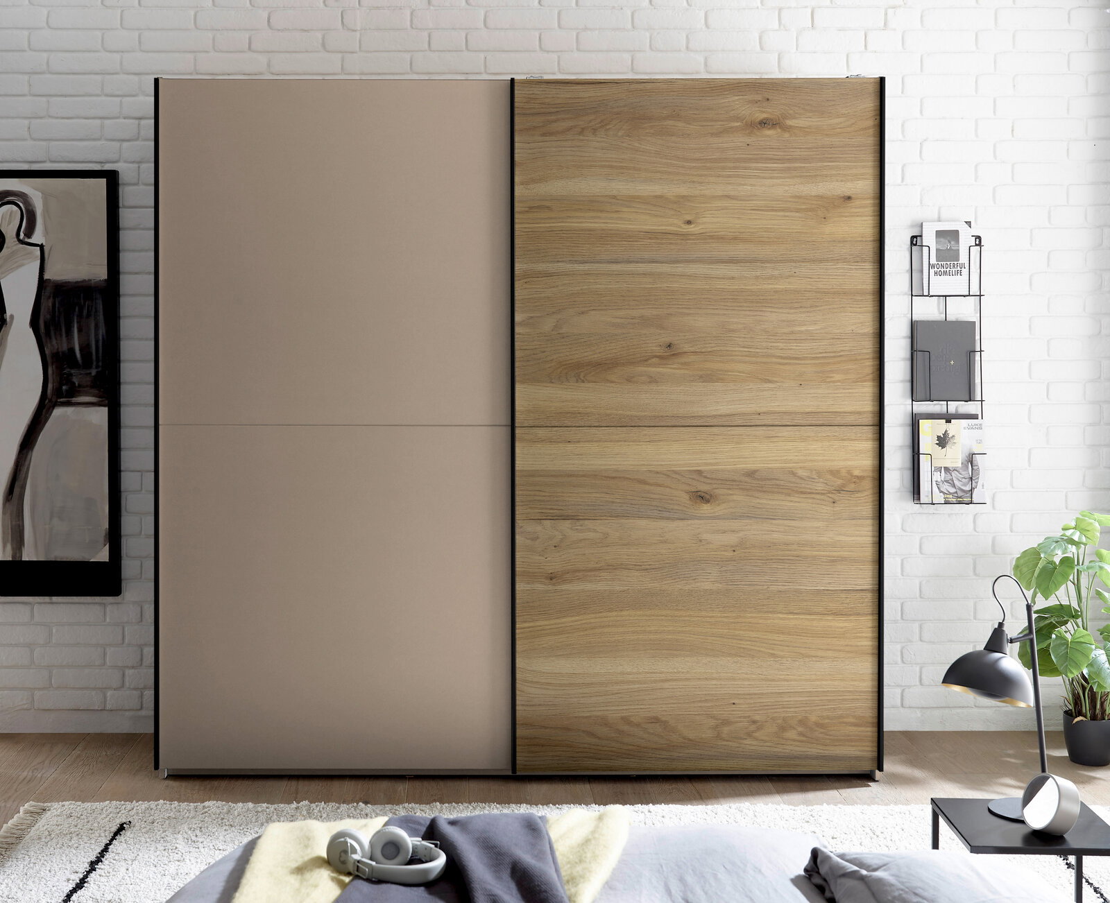 Moderner Kleiderschrank mit zwei Schiebetüren, links in Taupe und rechts in Holzoptik mit schwarzem Rahmen, frontal aus Augenhöhe im Schlafzimmer fotografiert