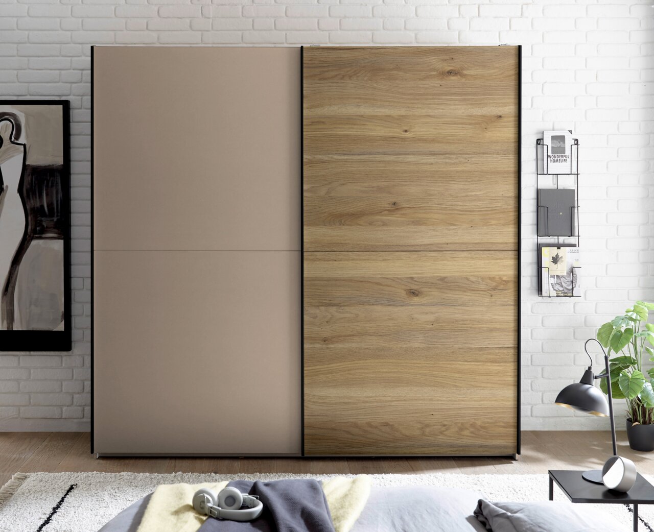 Moderner Kleiderschrank mit zwei Schiebetüren, links in Taupe und rechts in Holzoptik mit schwarzem Rahmen, frontal aus Augenhöhe im Schlafzimmer fotografiert