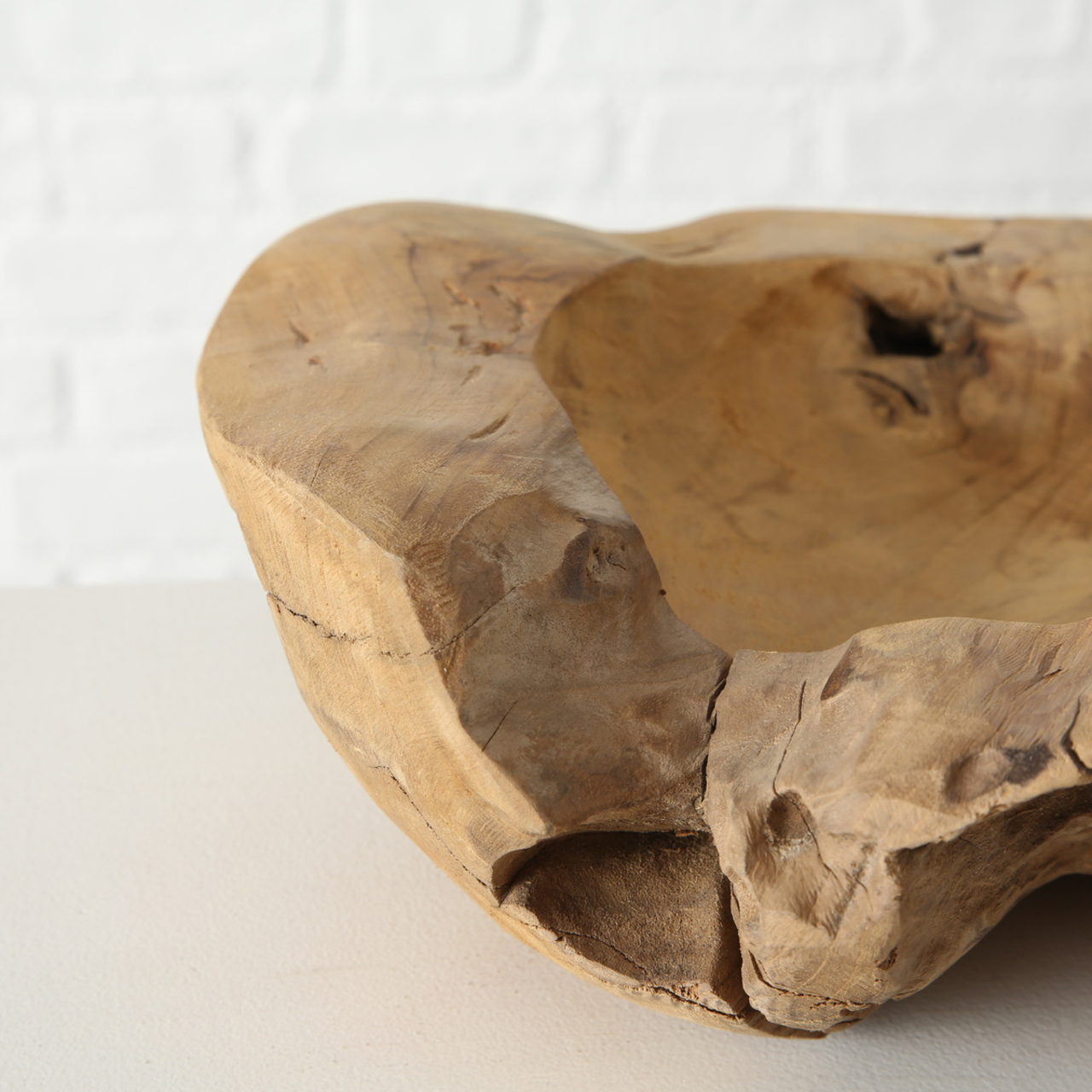 Nahaufnahme einer dekorativen Schale aus Teakholz mit natürlicher, rustikaler Oberfläche und unregelmäßiger Form.
