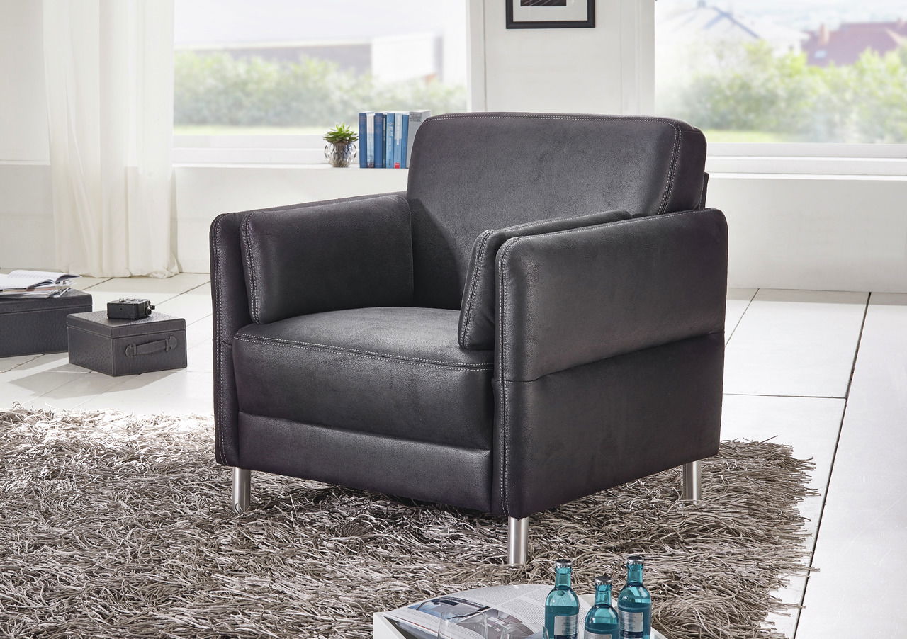 Moderner schwarzer Sessel mit Metallfüßen in einem hellen Wohnzimmer, seitliche Perspektive.