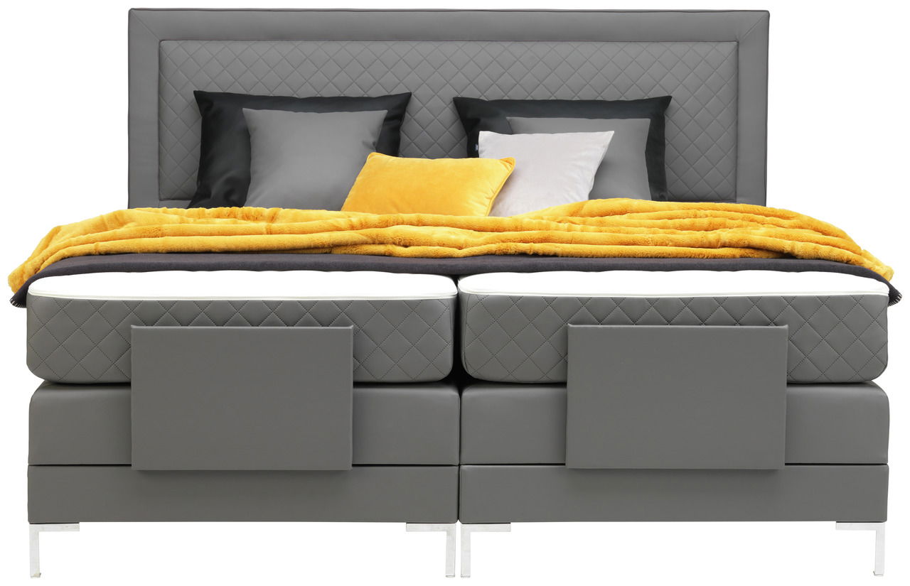 Graues Boxspringbett mit gestepptem Kopfteil, gelber Decke und Kissen, Frontalansicht