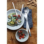 Vogelperspektive auf ein elegantes 4-teiliges Servier-Set aus Edelstahl, präsentiert mit gegrilltem Gemüse und Tomaten auf einem rustikalen Holztisch.