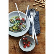 Vogelperspektive auf ein elegantes 4-teiliges Servier-Set aus Edelstahl, präsentiert mit gegrilltem Gemüse und Tomaten auf einem rustikalen Holztisch.