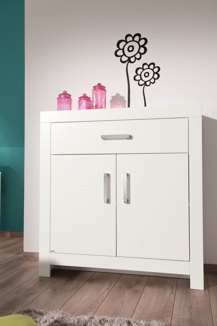 Weißes Highboard mit zwei Türen und einer Schublade, dekoriert mit rosa Gläsern, aus frontaler Perspektive fotografiert.