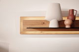 Frontale Ansicht eines modernen Wandboards aus Holz mit integrierter Beleuchtung, dekoriert mit stilvollen Vasen und einer Lampe.